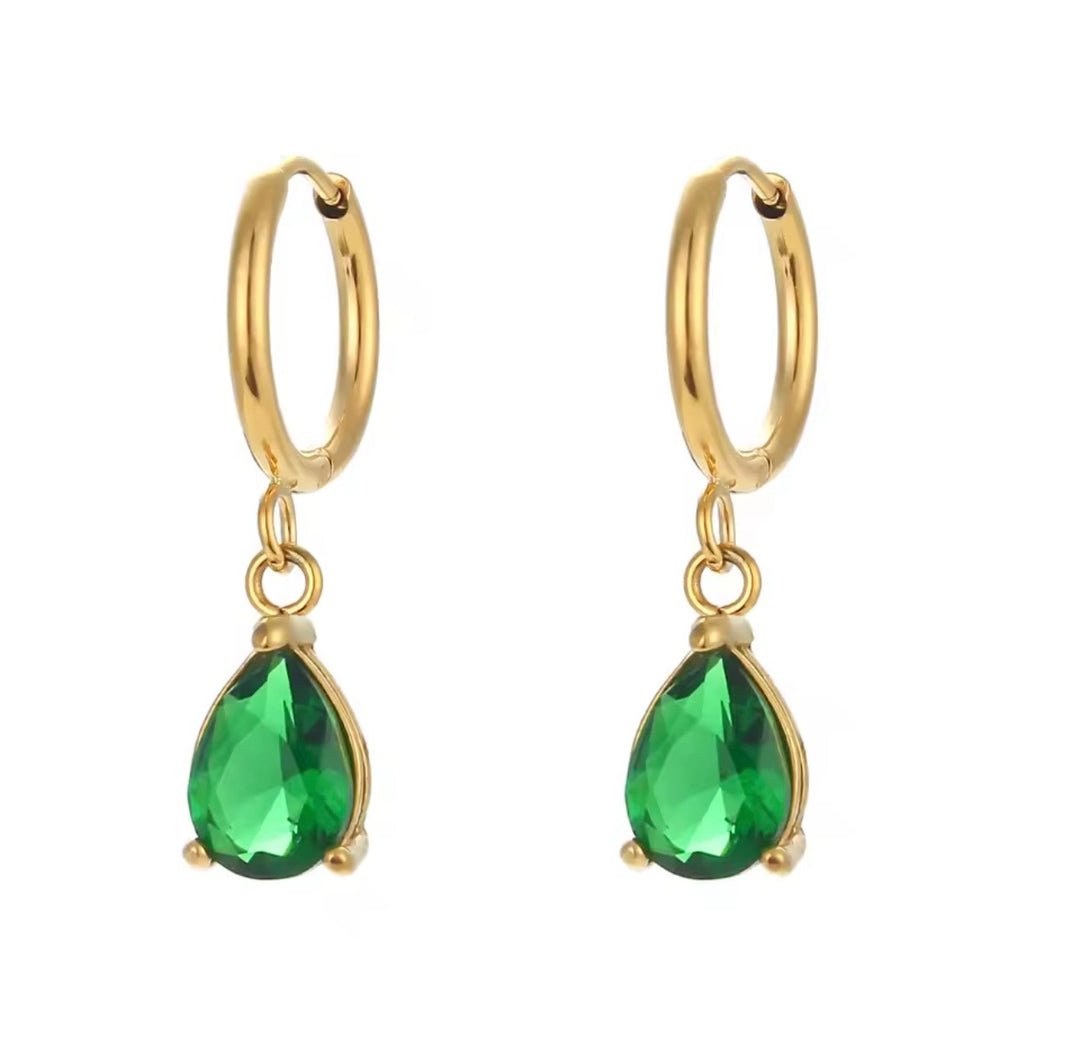 a pair of earrings with green gemstones