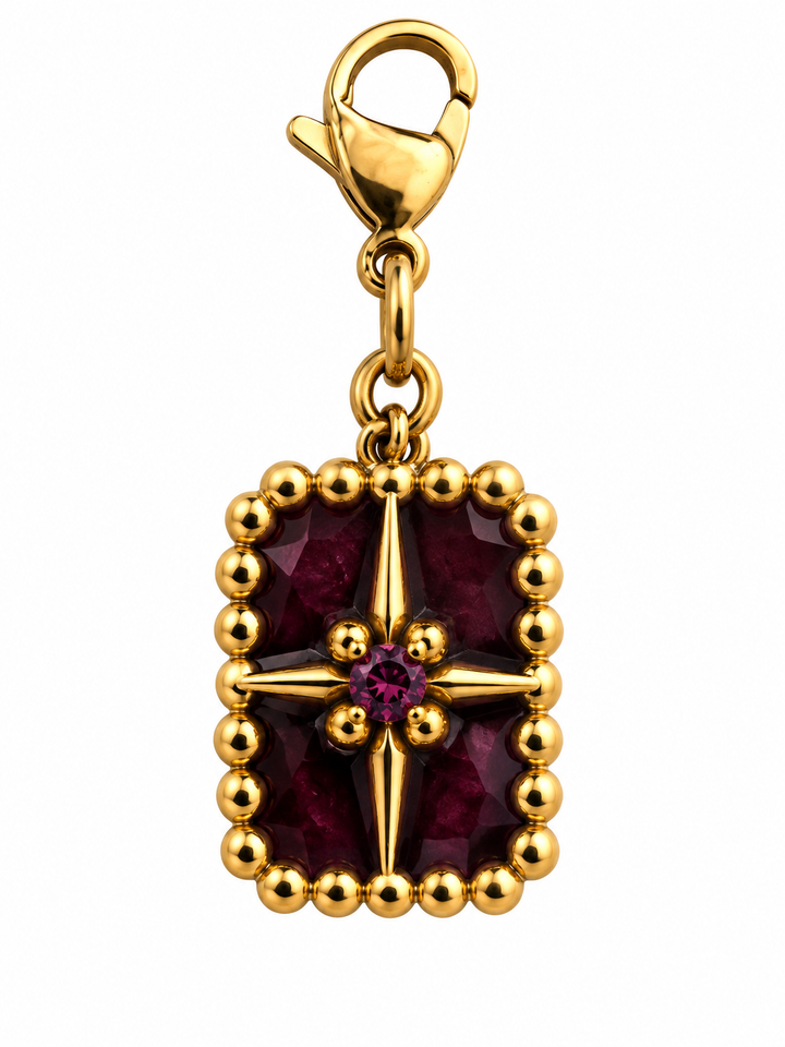 a gold necklace with a red stone and a star