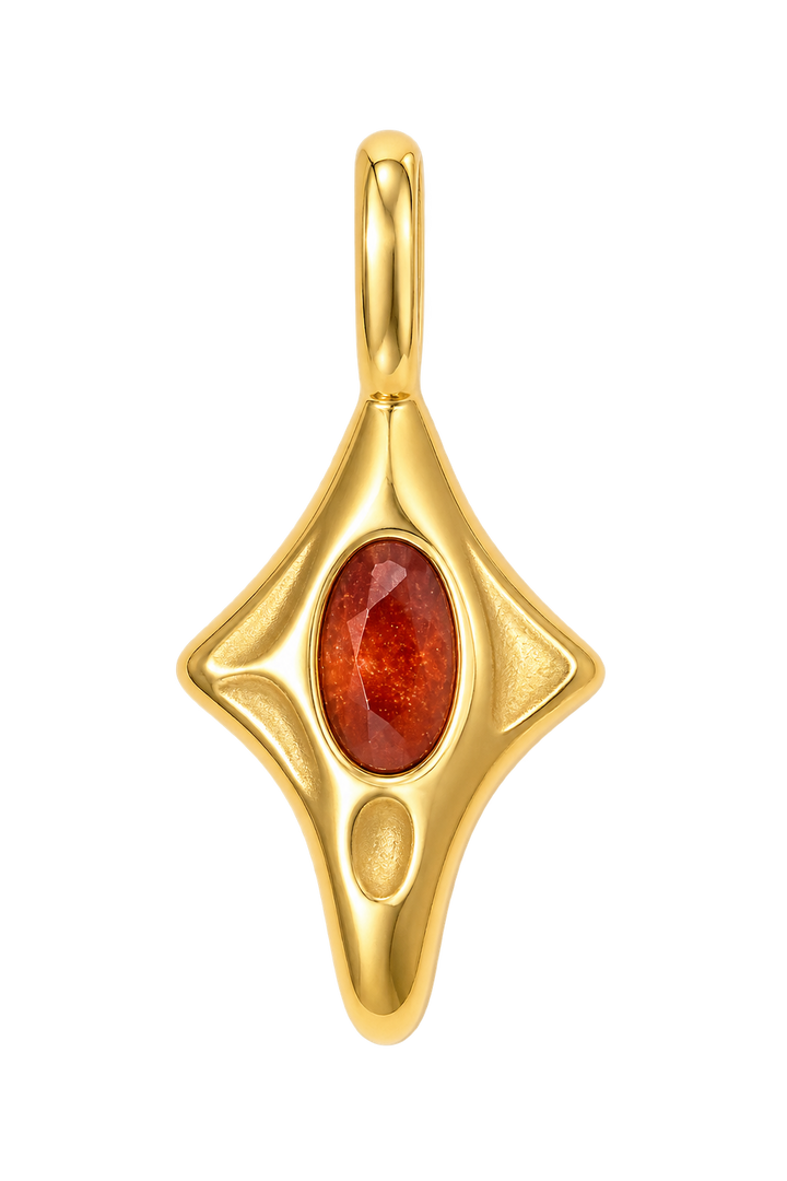 a gold pendant with a red stone