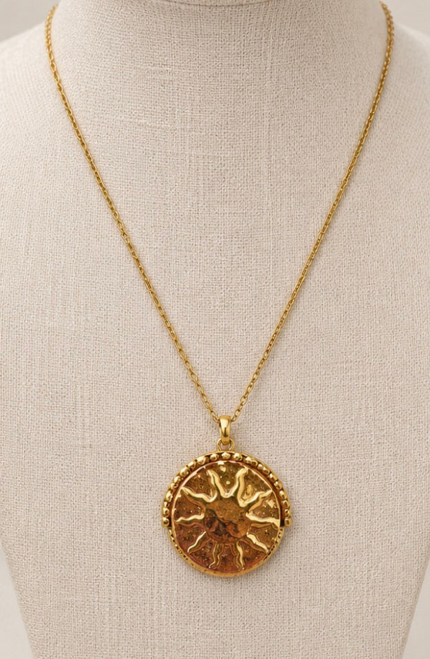a gold necklace with a sun pendant