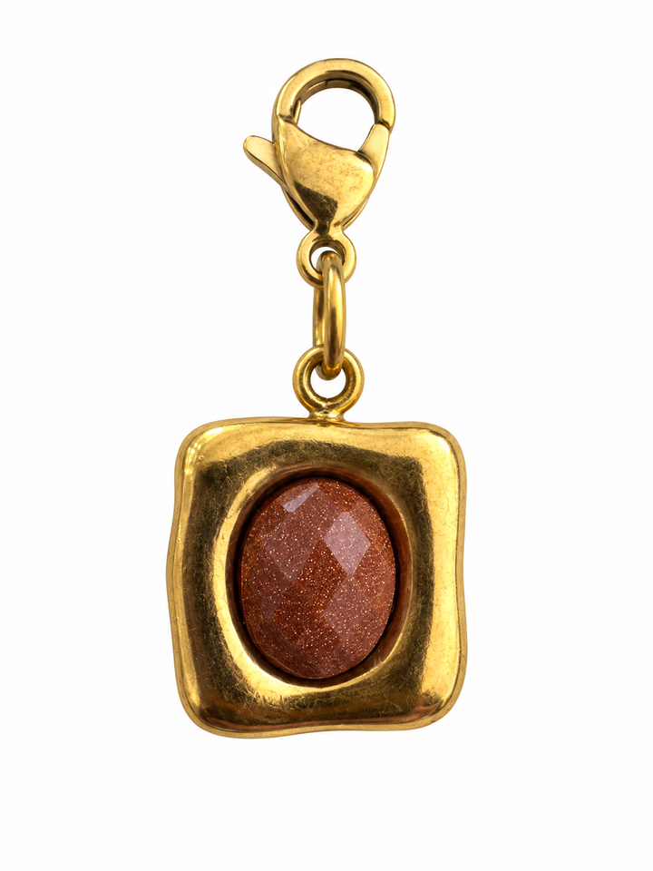 a gold square with a brown stone in the middle