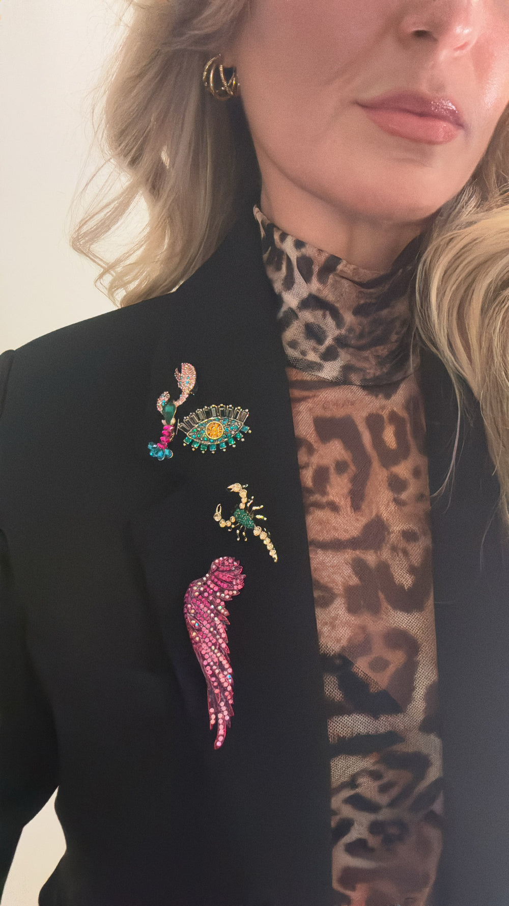 a woman wearing a leopard print shirt and a black jacket with brooches
