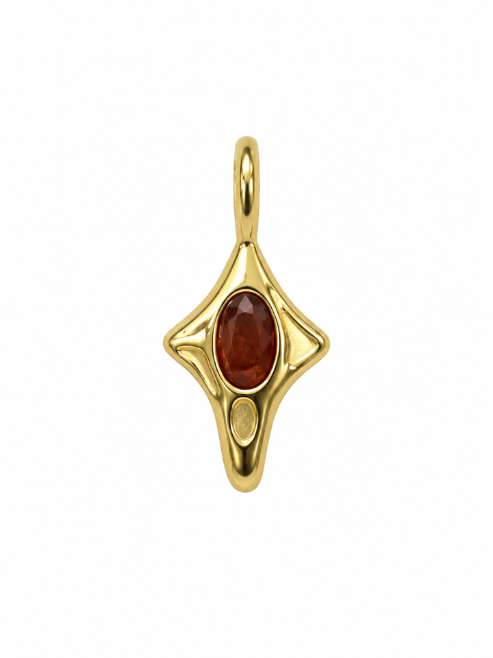 a gold pendant with a red stone